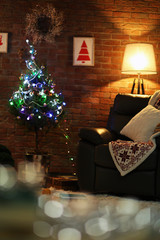 Living room interior with black armchair, lamp and Christmas tree on brick wall background