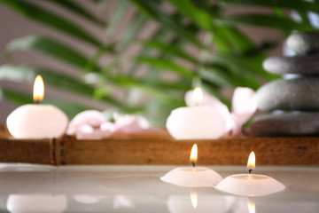 Fototapeta na wymiar Spa still life with candles in water on natural blurred background