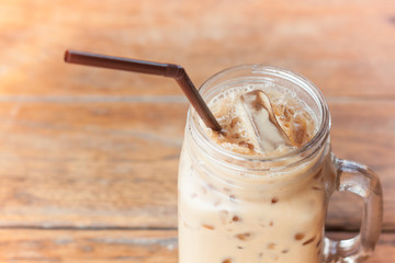 Glass of iced coffee on wooden table with vintage filter style