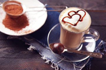 Milk coffee in glass cup with chocolate syrup on black wooden table