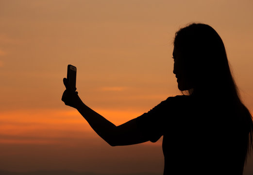 Silhouette Of Woman Taking Photo With Mobile Phone