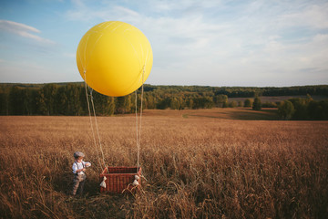 Obraz premium little boy traveler standing next to a aerostat in field