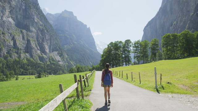 People walking in Switzerland alps. Woman hiker tourist hiking on hike in Swiss alpine nature landscape in Lauterbrunnen valley in Bernese Oberland, Schweiz, Europe. RED EPIC SLOW MOTION.