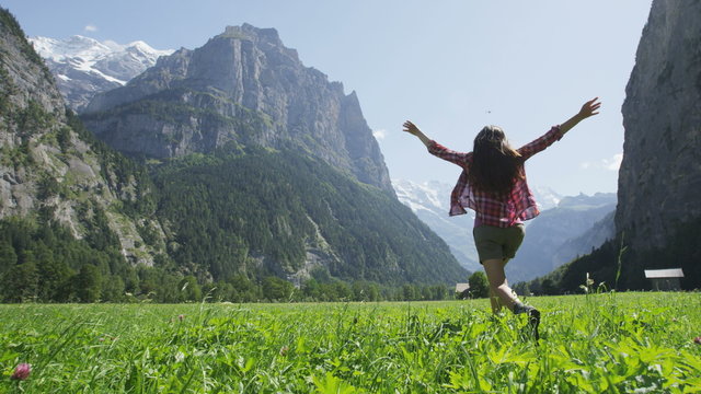 Happy woman having fun running in field nature excited of joy happiness. Joyful active lifestyle with free girl enjoying freedom, Lauterbrunnen valley, Swiss Alps, Switzerland. RED EPIC SLOW MOTION