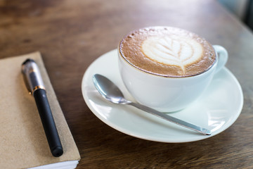 Coffee cup and notebook on table background.