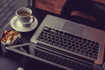 A cup of coffee and  laptop on a table.
