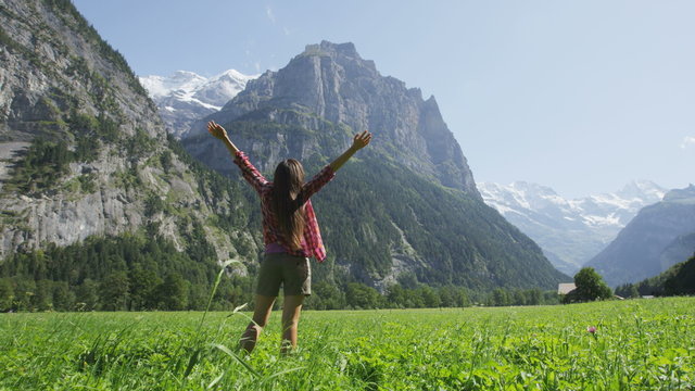 Free happy woman with arms outstretched in freedom nature excited of joy happiness. Cheerful active lifestyle with girl serene rasing arms in Lauterbrunnen valley, Swiss Alps, Switzerland. SLOW MOTION