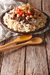 kushari of rice, pasta, chickpeas and lentils close up on the table. vertical
