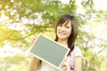 Fototapeta premium Young Asian college girl student showing blank chalkboard