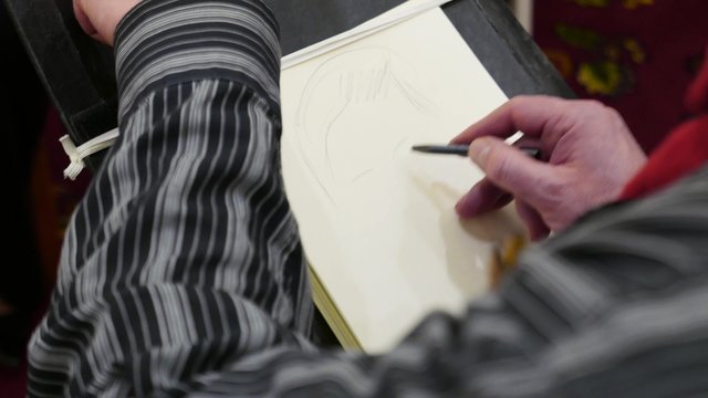 painter painting a woman's caricature portrait on paper canvas, with pencil