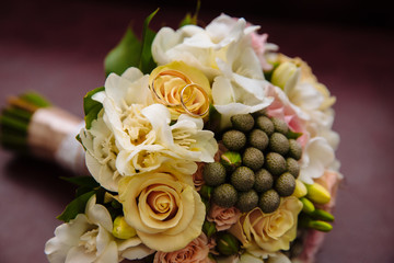 Rings on the beautiful wedding bouquet in rustic style with rose