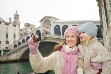 Obraz premium Mother and daughter taking photos in front of Ponte di Rialto