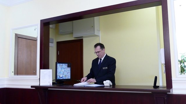 Apartment Concierge. Man looking to file with documents at the concierge desk.