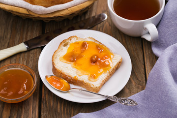 Bread with butter, apricot jam and a Cup of black tea