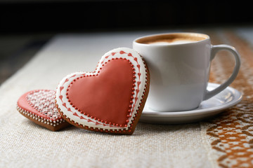 Celebrating delicious. Glaze decorated heart shaped cookie with a cup of coffee on a cafe table