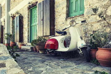 Vieux scooter garé par le mur dans la rue vide de Karpathos, Grèce. Post traité avec filtre vintage.