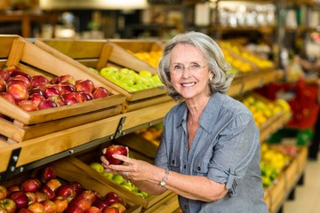 Smiling senior woman picking apple
