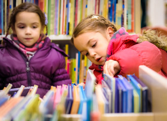 Little girl is choosing a book in the library
