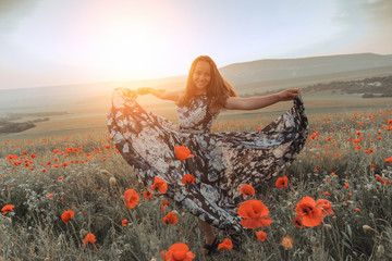 beautiful girl in a poppy field at sunset. concept of freedom