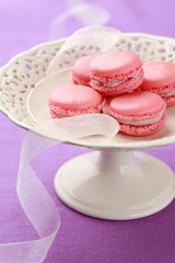 Pink macarons with buttercream filling on cake stand