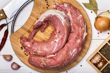 Pork tenderloin on a cutting board with ingredients, top view