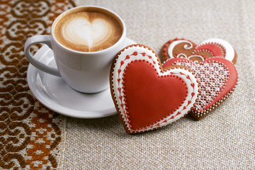 Taste addiction. Top view shot of Valentine’s day gingerbread decorated cookies and a cup of cappuccino on the restaurant table