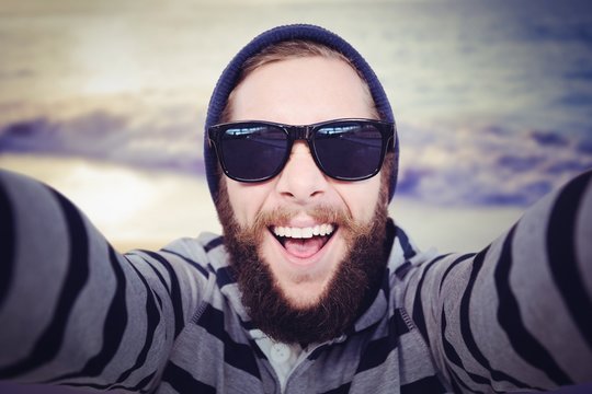 Composite image of portrait of happy hipster wearing sunglasses