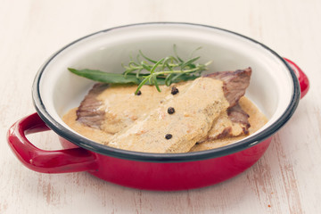 fried pork with pepper sauce in dish on white wooden background