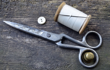 Vintage Background with sewing tools.Sewing kit. Scissors,button, bobbin with thread,needle and thimble on the old wooden background