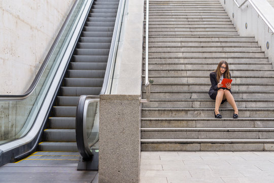 Office woman working in the stairs near scalator with tablet