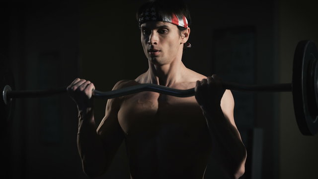 Closeup portrait of a muscular man workout with barbell at gym. 