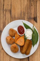 appetizers with sauces on white plate on brown wooden background