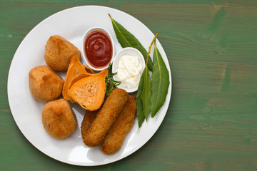 portuguese appetizers with sauces on white plate on green background