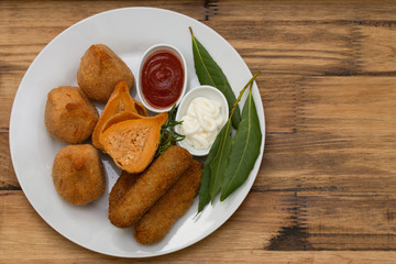 portuguese appetizers with sauces on white plate on brown background