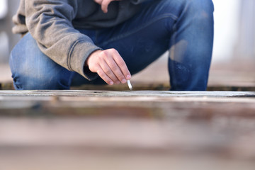 Hand of a young man how wants to extinguish cigarette on a old b