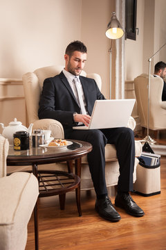 Young businessman working with portapble computer sit on armchair.