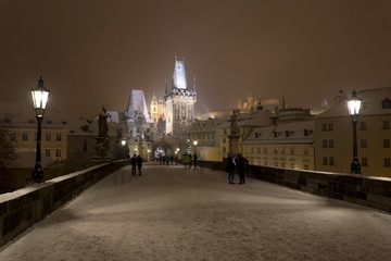 Fototapeta na wymiar Night snowy Prague gothic Castle, Bridge Tower and St. Nicholas' Cathedral from Charles Bridge with its Statues, Czech republic