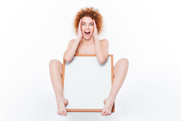 Amazed naked woman sitting with blank board © Drobot Dean