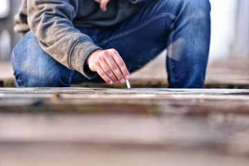 Hand of a young man extinguishing cigarette on a old bridge. Con