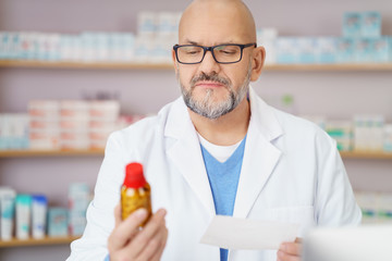 apotheker schaut mit ernstem gesichtsausdruck auf ein medikament