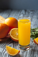 Naklejka na ściany i meble Glass of fresh orange juice, slices of orange and mint leaves on wooden table. Focus on orange slice.