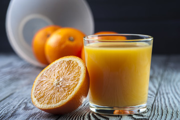 Fresh Orange juice and oranges on wooden table. Focus on glass.
