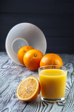 Fresh Orange juice and oranges on wooden table. Focus on glass.