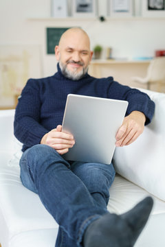 mann liegt auf dem sofa und schaut auf tablet-pc
