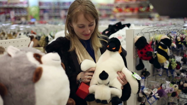 The girl is shopping, she chooses children's soft toy
