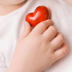 A small red heart in hand of child. Love. Happiness. Care. Healthcare. Childhood.