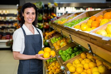 Portrait of a smiling worker taking a fruits