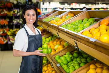 Portrait of a smiling worker taking a fruits
