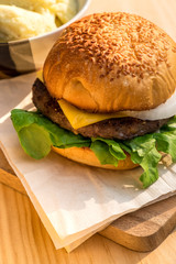 Yummy Beef and cheese Hamburger place on wood tray beside Potato