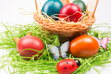 Easter eggs in wicker basket on white